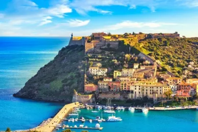 Hügelige Küste in Porto Ercole mit Festung und bunten Häuserfassaden.