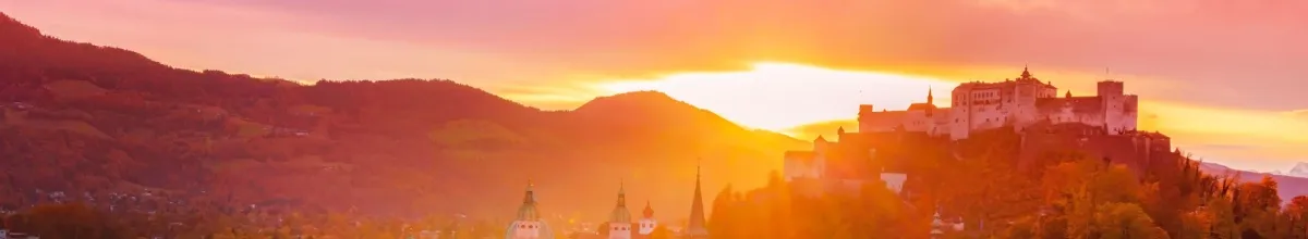 Die Festung Hohensalzburg im Sonnenuntergang mit den Alpen im Hintergrund.