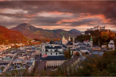 Die Festung Hohensalzburg von oben und im Sonnenuntergang fotografiert. Im Hintergrund die Alpen.
