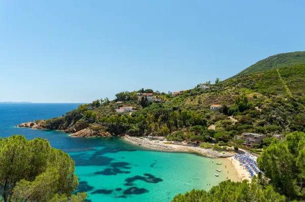 Heller Sandstrand mit Sonnenschirmen, umgeben vom türkisblauen Meer.