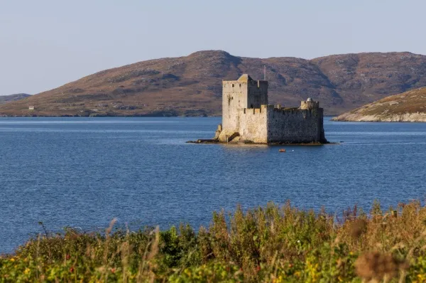 Die Kisimul Castle thront auf ihrer Insel vor der Küste Castlebays. Im Hintergrund ist die Natur der Insel zu sehen.