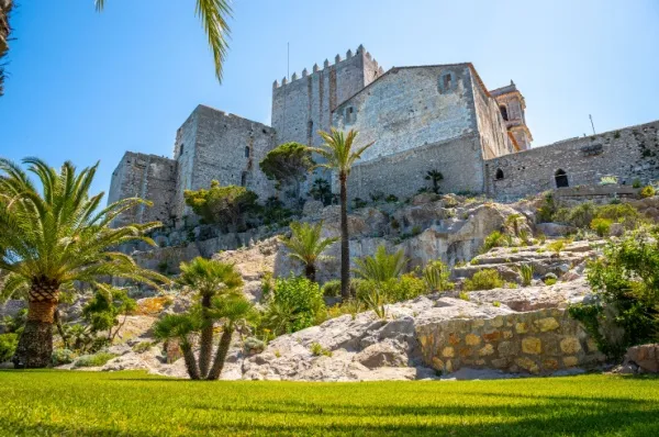 Die Burg Peñíscola Hoch oben auf dem Berg steht die Burg Peñíscola umschlossen von Palmen