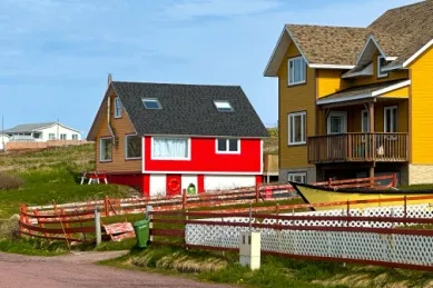 Ein rotes und gelbes Haus in grünem Umland auf St. Pierre und Miquelon.
