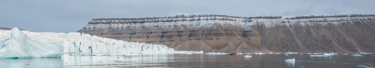 Die eisige und felsige Küste von Crocker Bay vom Wasser aus fotografiert mit einem kleinen Kajak am Tag.