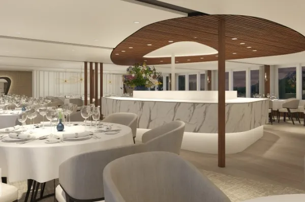 Restaurant auf der AMADEUS Amara Rendering des Restaurant-Bereichs auf AMADEUS Amara. Im Vordergrund ein weiß eingedeckter Tisch mit Weingläsern und weißen Sesseln davor, im Hintergrund eine weiß marmorierte Bar mit hölzerner Decke.