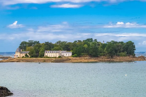 Die nahegelene Insel Île Tristan umgeben vom Meer am Tag mit Gebäuden und einem Wald.