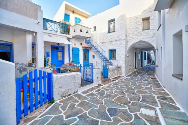 Gasse im Dorf Chora mit weißen Häuserfassaden und blauen Zäunen und Fensterläden.