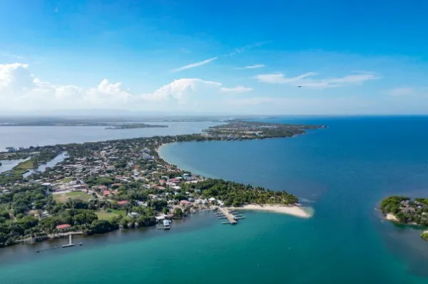 Placencia von oben Luftaufnahme auf die Küste von Placencia am türkisblauen Meer unter blauem Himmel.