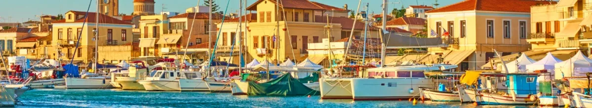 Kleine Yachten und Fischerboote am Hafen von Ägina bei Sonnenschein.