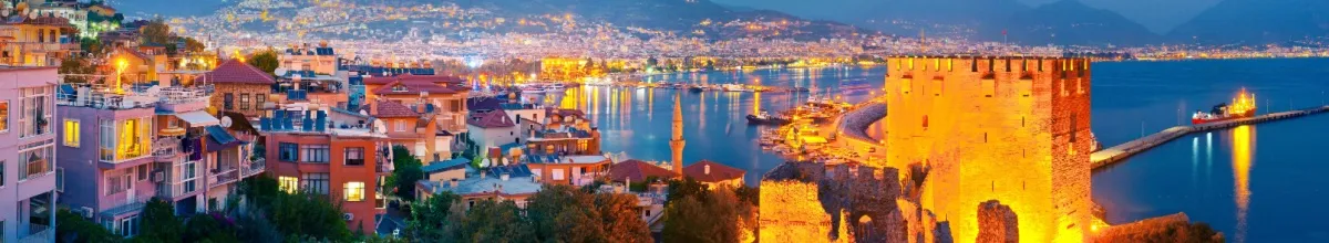 Beleuchtete Häuser und Turm in Alanya bei Nacht.
