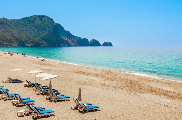 Weißer Sandstrand mit Liegestühlen und türkisfarbenem Meer.
