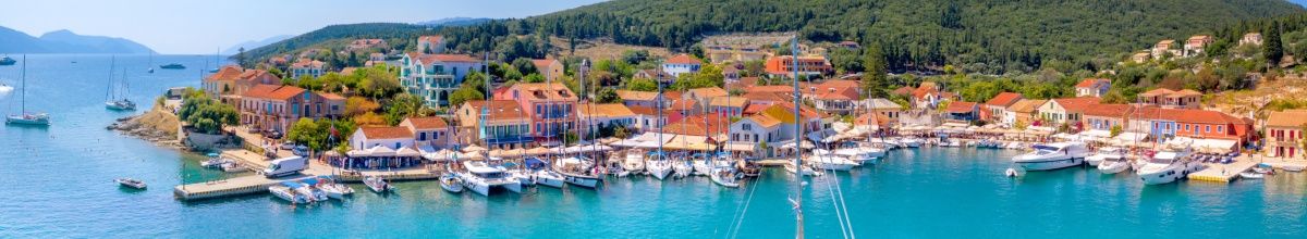 Jachten und Fischerboote am Hafen von Fiskardo am türkisblauen Meer.