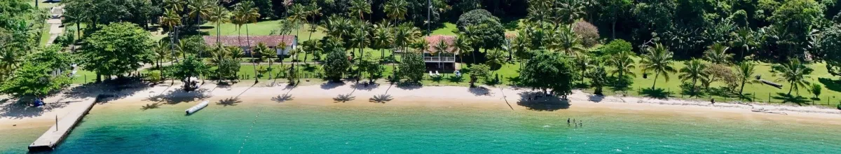 Sandstrand und grüne Natur am türkisfarbenen Meer.