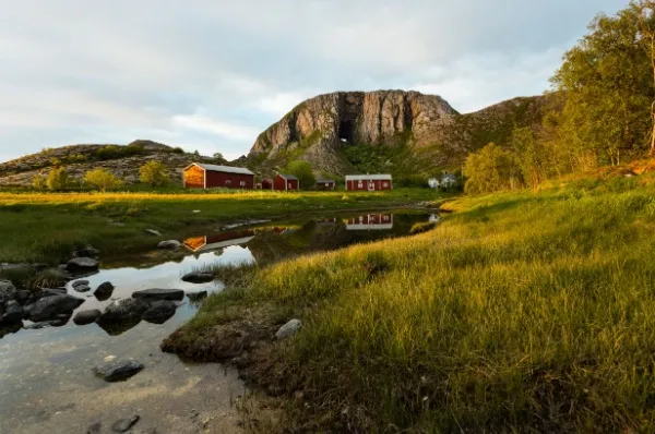 Der Fels Torghatten ragt im Hintergrund auf und beugt sich über die kleinen roten Häuser.