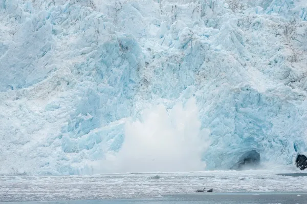Der Aialik-Gletscher kalbt. Ein großes Stück Eis bricht ab und landet im Ozean.