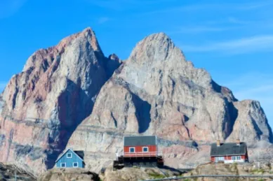 Im Hintergrund ragt der Berg auf Uummannaq empor, der durch seine Spaltung wie ein Herz aussieht. Im Vordergrund sind kleine Häuser zu sehen.