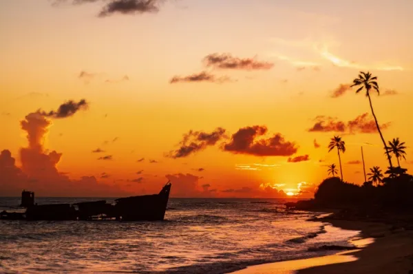 Sonnenuntergang auf Vieux Fort Ein orangener Sonnenuntergang in Vieux Fort auf St. Lucia in der Kraibik. Ein Wrack liegt im Meer.