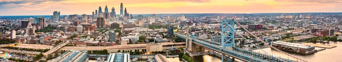Eine langgezogene Skyline Philadelphias mit vielen Sehenswürdigkeiten und dem Hafen im Vordergrund.