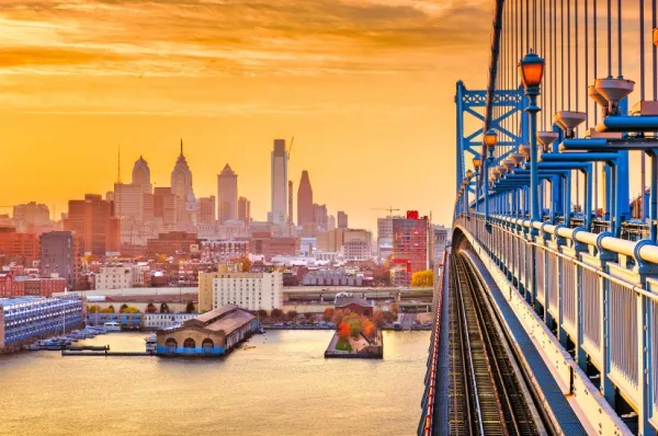 Der Hafen von Philadelphia aufgenommen von der Seite einer Brücke mit einem orangenen Sonnenuntergang.