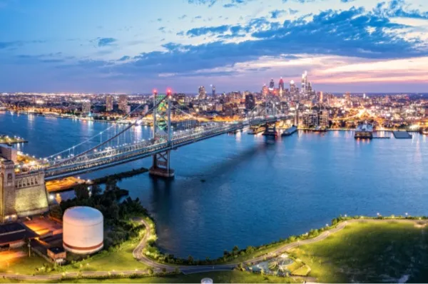 Die Skyline von Philadelphia mit einer Brücke über den Fluss und den Lichtern der Stadt im Hintergrund.
