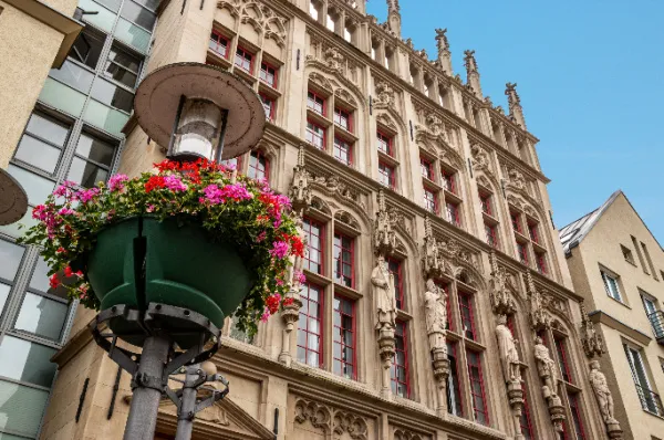 Ein verziertes Stadthaus Ein reich verziertes Stadthaus in Wesel mit einem Blumenkübel an einer Laterne im Vordergrund am Tag.