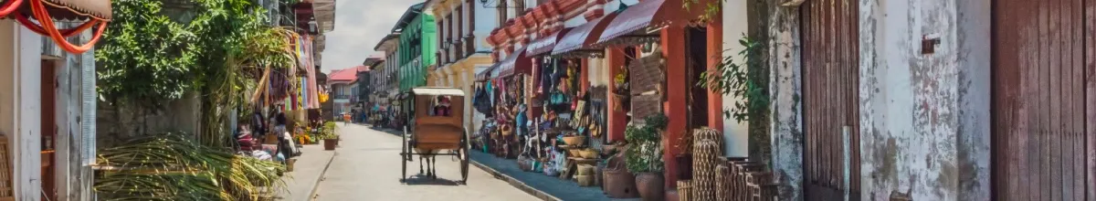 Die bunt-gemixten Häuser der Stadt reihen sich auf der Seite. Eine Pferdekutsche reitet durch die Straßen.