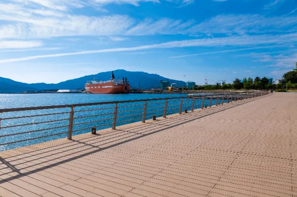 Ausblick über die Promenade vom Hafen von Tsuruga mit einem roten, großen Schiff in der Ferne am Tag.