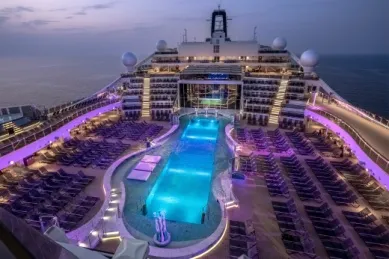 Rendering: Abendliche Ansicht des Poolbereichs La Plague auf MSC World America. Der Pool selbst ist in blau, der Liegebereich in lila erleuchtet.
