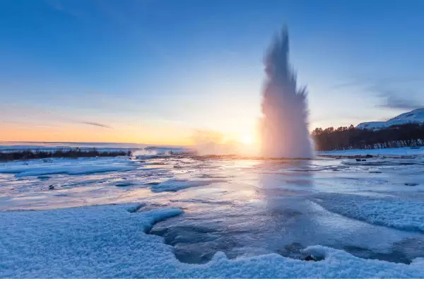 Eruption des Strokkur Geyser in Island. Winterkalte Farben, Sonnenlicht durch Dampf