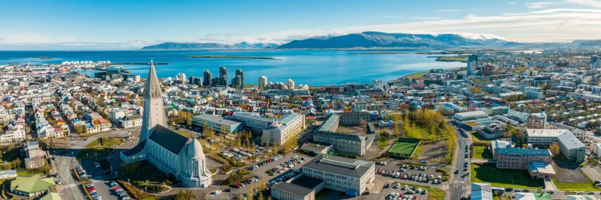 Eine Totale der Stadt Reykjavik Die Stadt im Sonnenlicht, mit dem Meeresbusen und dem Stadtberg im Hintergrund.