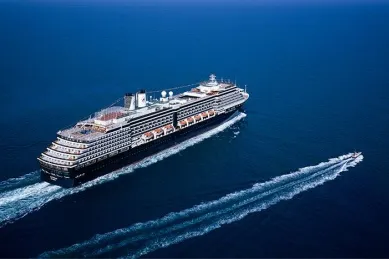 Vogelperspektive auf die Oosterdam auf dem Meer. Rechts daneben fährt ein kleines Schnellboot.