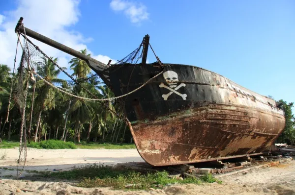 Ein alten Piratenschiff mit Totenkopf Logo liegt am Strand von Ambodifototra und rostet vor sich hin.