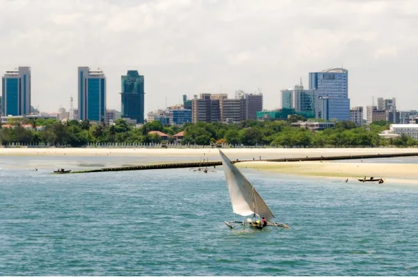 Daressalam Strand Ein Segelboot am Strand von Daressalam mit der Skyline der Stadt im Hintergrund.