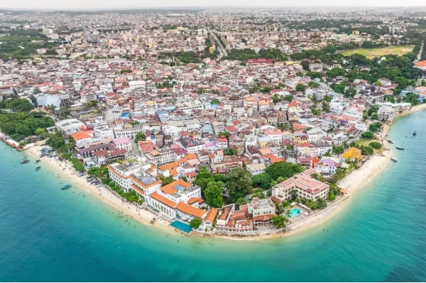 Die Stadt Sansibar an einem Zipfel der Insel mit Strand und der historischen Altstadt aus der Vogelperspektive.