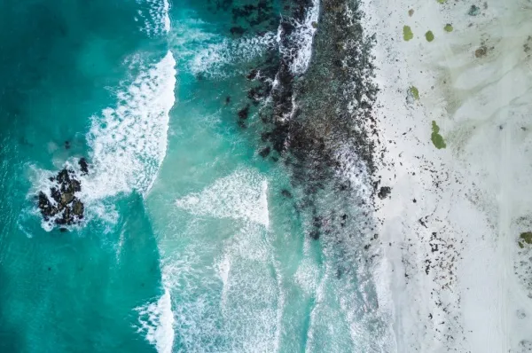 Die Brandung am Strand Luftaufnahme des türkisen Meeres, wie es seicht an den Strand Coquimbos brandet am Tag.