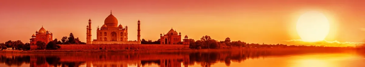 Der Taj Mahal vom Fluss aus fotografiert in einem raten Sonnenuntergang am Ufer.