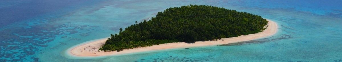 Eine kleine, unbewohnte Insel mit dünnem Sandstrand in strahlend blauem Meer.