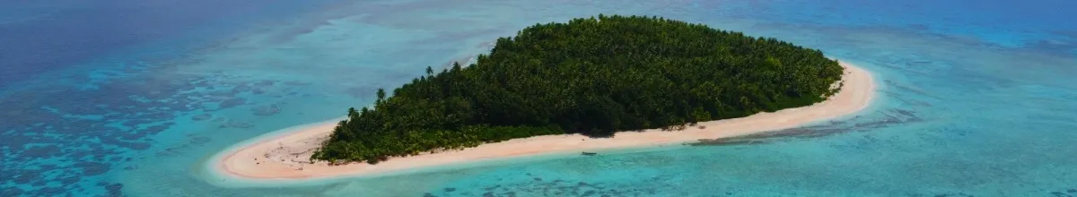 Eine kleine, unbewohnte Insel mit dünnem Sandstrand in strahlend blauem Meer.
