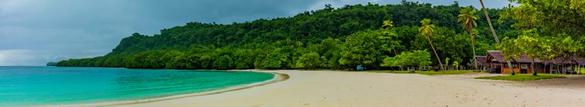 Der Strand von Luganville mit champagnerfarbenen Sand und Regenwand im Hintergrund, der an türkises Wasser mündet.