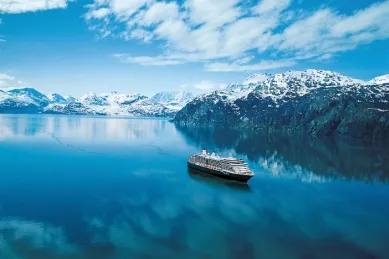 Westerdam fährt durch eine von Bergen und Schnee bedeckte Bucht.