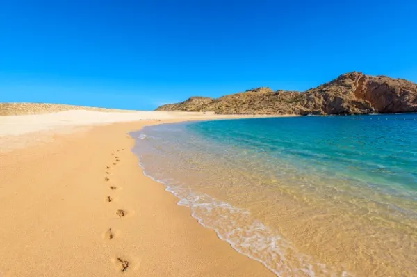 Heller Sandstrand, umgeben vom klaren, blauen Meer.