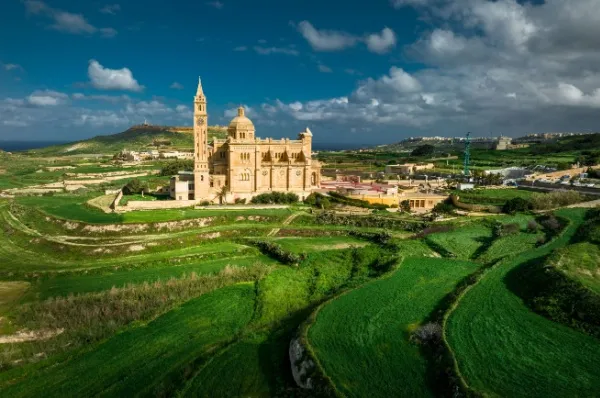 Die Basilika ta’ Pinu in Gozo umringt von grüner Landschaft und freundlichem Himmel.