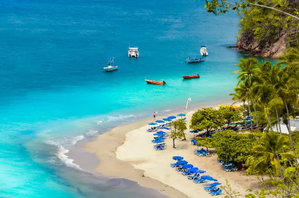 Eine natürlicher, kleiner Sandstrand auf der Isla Tortuga mit einigen Booten vor der Küste und malerischem türkisen Wasser bei Sonnenschein.