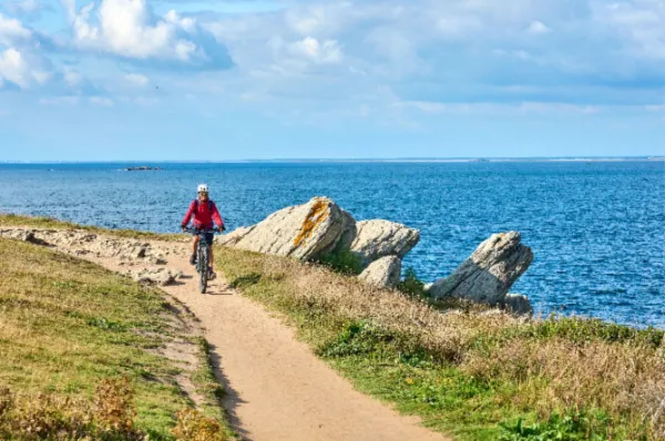 Ein Radfahrer, der die Côte Sauvage entlangradelt bei Sonnenschein, im Hintergrund das Meer.