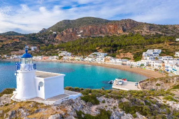 Eine kristallklare Bucht auf Kythira mit einer weiß-getünchten Kirche im Vordergrund und grünen Hügeln in der Ferne, dazwischen ist eine Stadt.