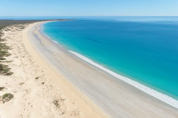 Weitläufiger heller Sandstrand in Broome mit türkisfarbenem Wasser.