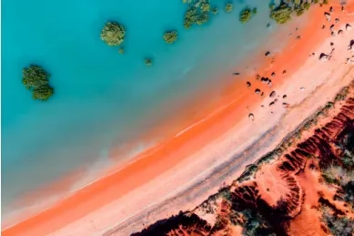 Luftaufnahme vom orangenen Sandtsrand mit türkisblauem Wasser in Broome.