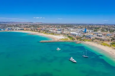 Luftaufnahme der Küste von Geraldton in Australien mit Sandstrand, der Innenstadt und kleinen Booten.