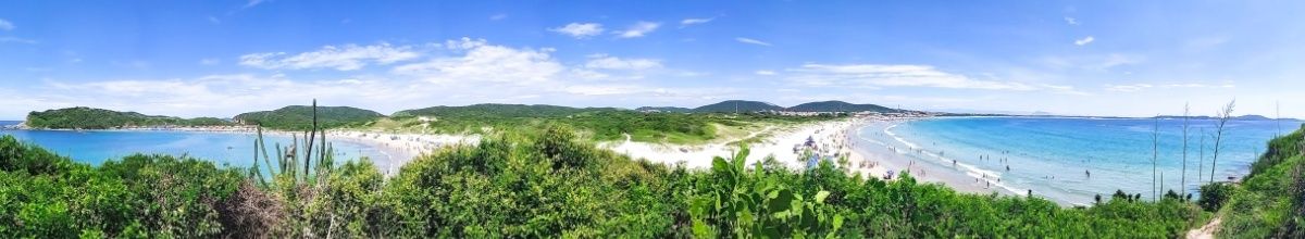 Panoramablick auf zwei Sandstrände in Cabo Frio, umgeben von grüner Natur.