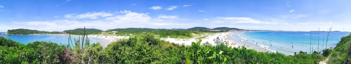 Panoramablick auf zwei Sandstrände in Cabo Frio, umgeben von grüner Natur.